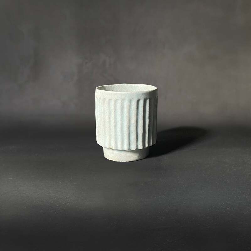 Hand-built and carved raku cup with seafood matt glaze.