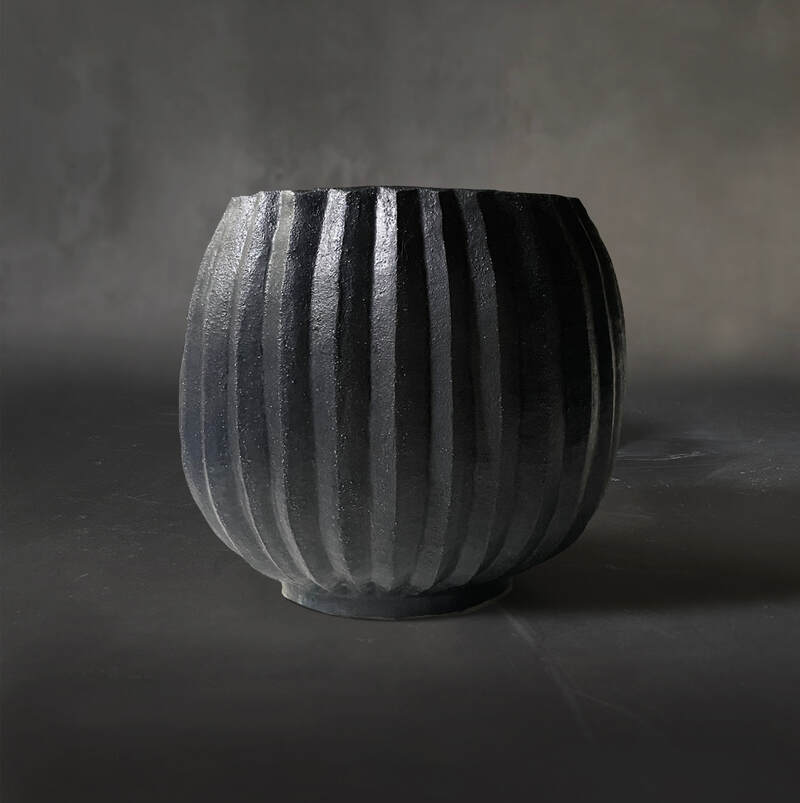 Hand-built and carved pleated raku pot/vase with matt black glaze.